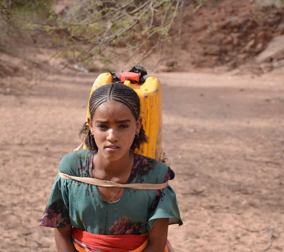 Young girl with water container on back.